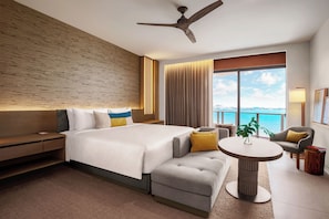 A modern hotel room with a large bed, a seating area with a table, a ceiling fan, and a view of the ocean. - Grand Hyatt Grand Cayman Resort & SPA (Seven Mile Beach)