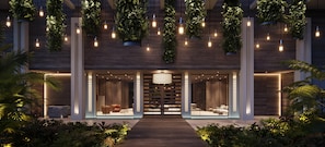 Een moderne gevel van een gebouw met houten lambrisering, hangende planten en een centraal hanglamp.