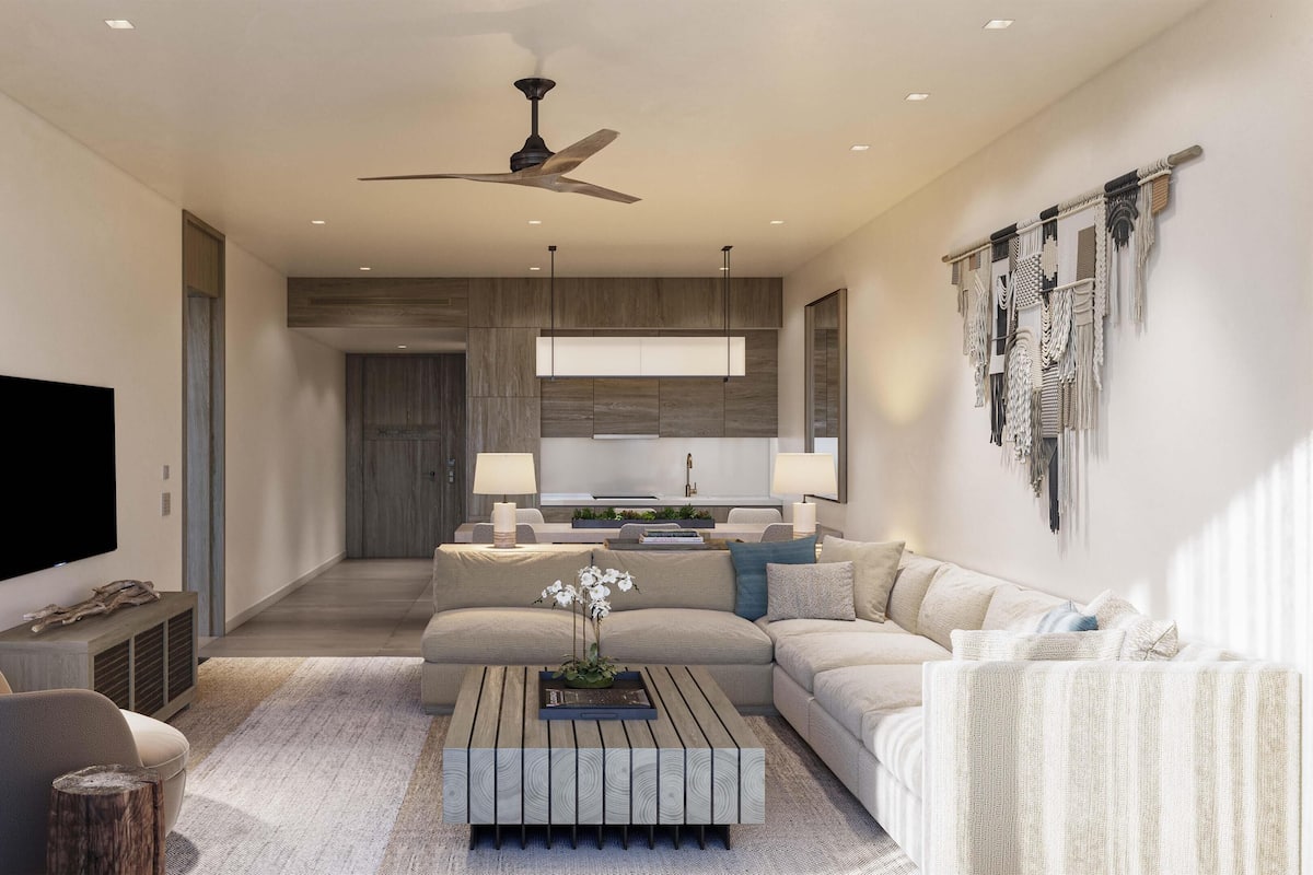 A modern living room with a sofa, coffee table, and a TV. There is a ceiling fan and recessed lighting.