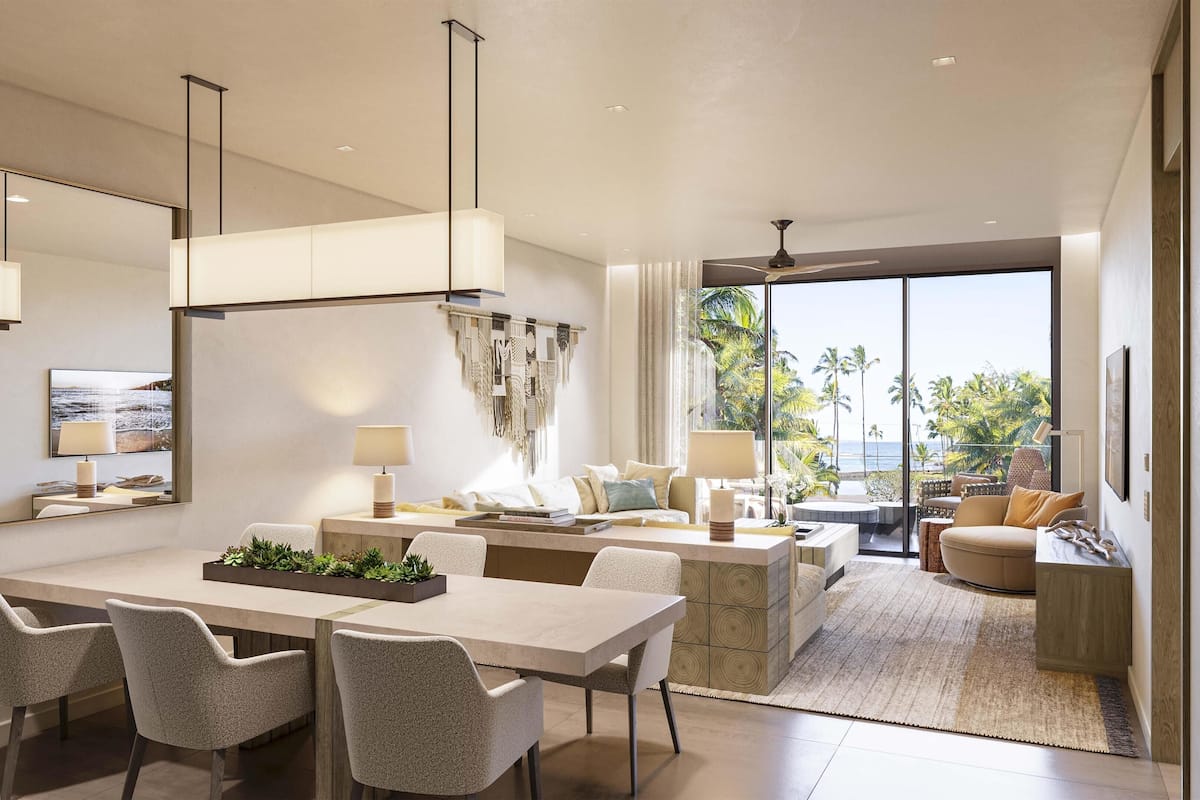 A spacious living area with a large dining table, comfortable seating, a kitchen area, and a view of the ocean.