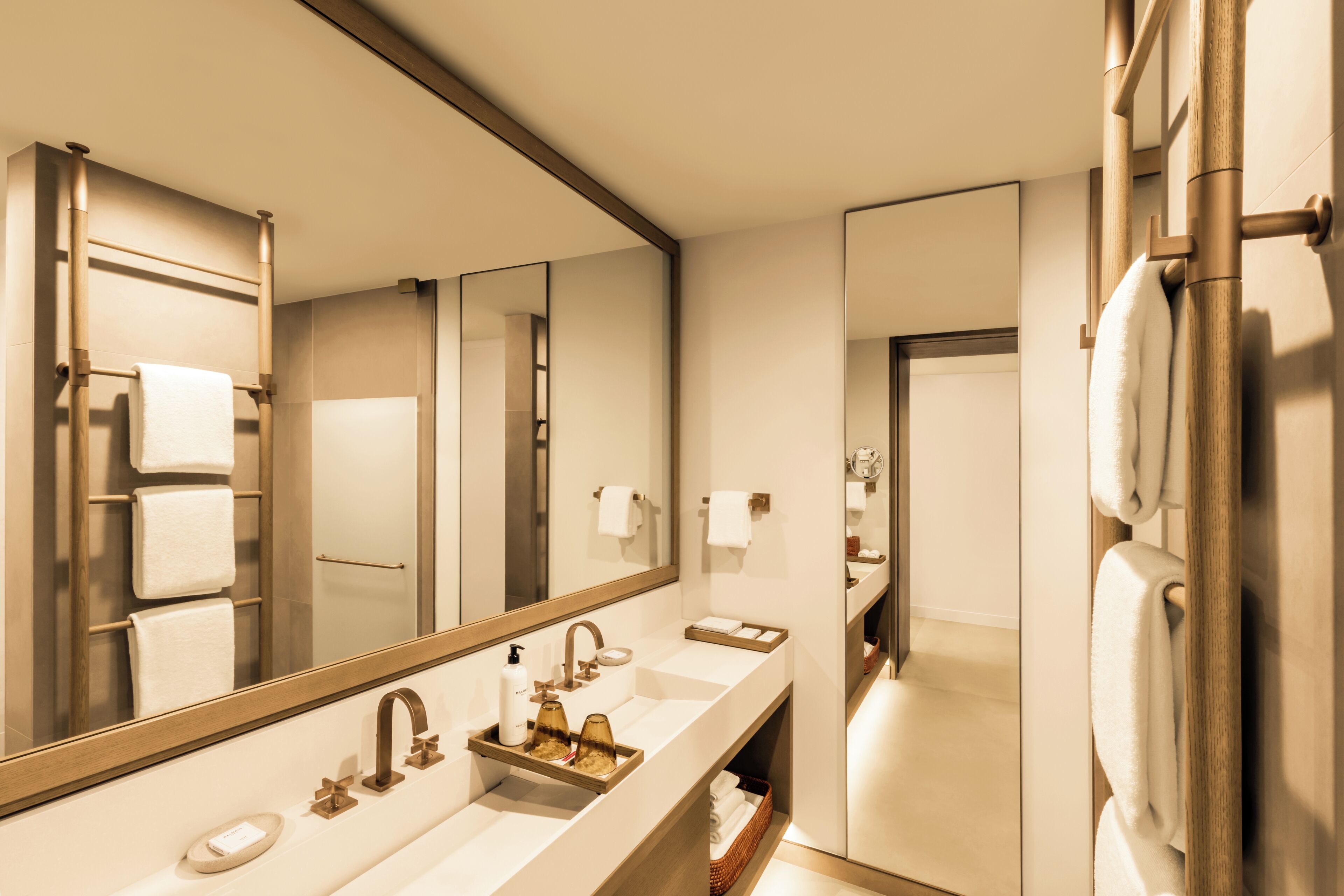 A modern bathroom with a large mirror, dual sinks, and a towel rack.