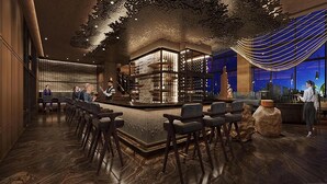 Zona de bar moderna con barra, asientos y estantería para vinos.