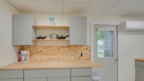 Una cucina compatta con mobili chiari in legno, un piano di lavoro in legno e una piccola finestra.