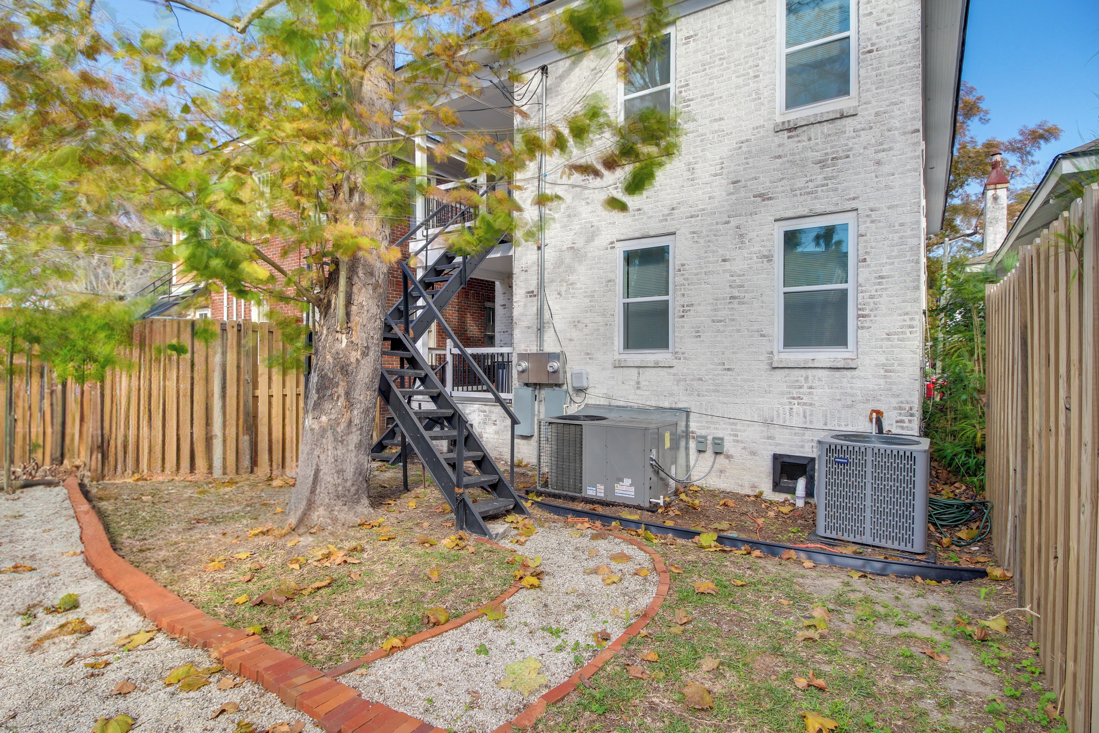 A residential building with a brick exterior, a wooden fence, and a tree with autumn leaves.