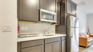 A modern kitchen with dark wood cabinets, stainless steel appliances, and a white countertop.
