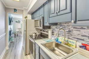 Una cocina moderna con gabinetes grises, un lavamanos de acero inoxidable y un salpicadero de azulejos.