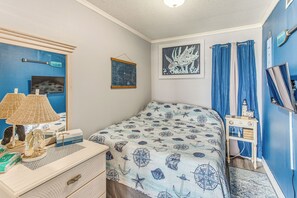 Une chambre à coucher comprenant un lit, une commode, une lampe et une décoration sur le thème de la marine.