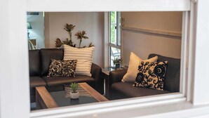 Un salon moderne avec un ensemble de canapés, une table basse et des coussins décoratifs.
