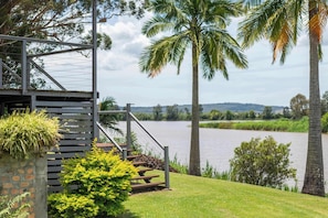 A lakeside view with a staircase, palm trees, and a stone wall.