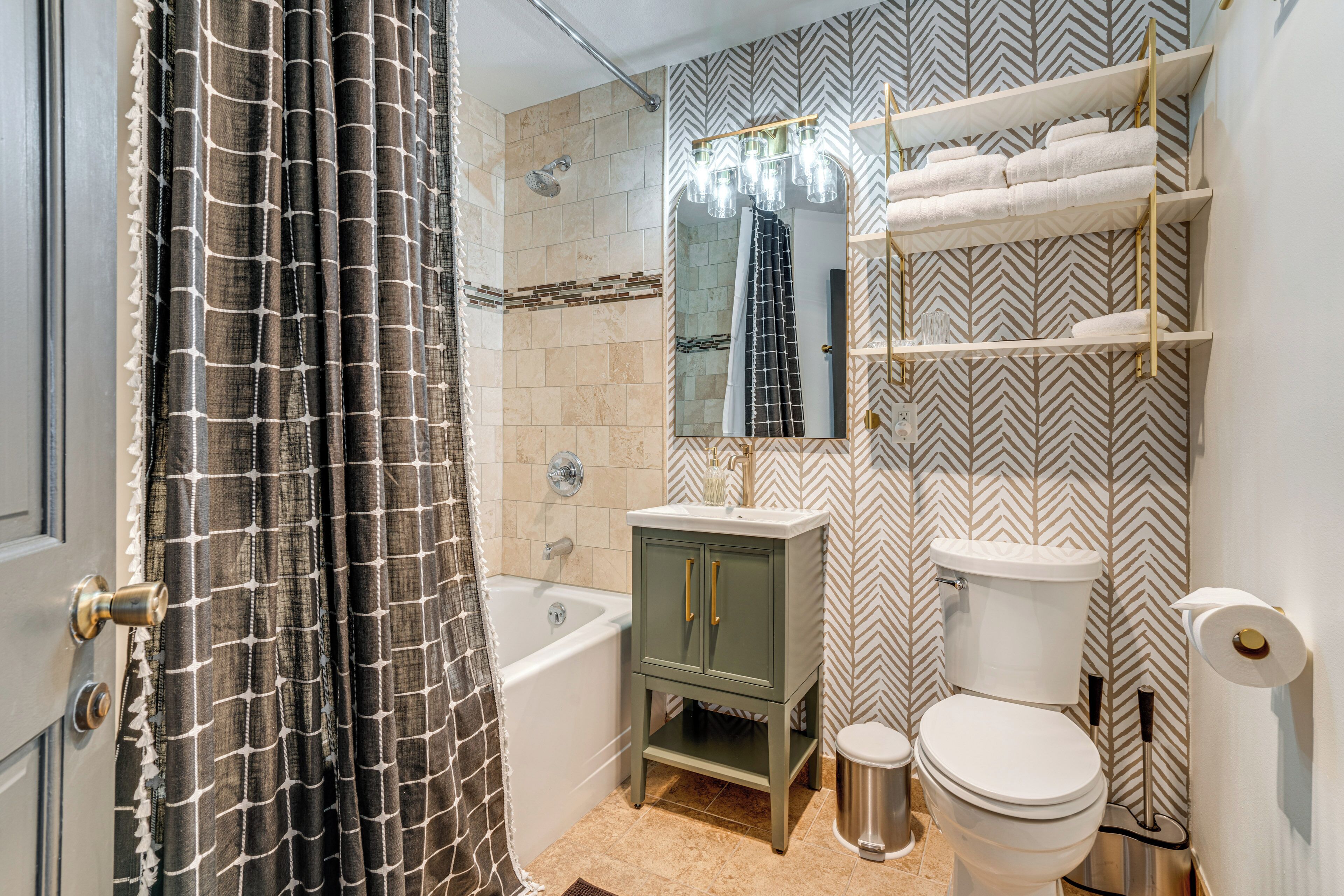 A bathroom with a bathtub, a toilet, a vanity with a mirror, and a shower curtain.
