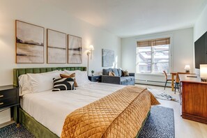 A hotel room with a large bed, a sofa, a desk, and a view of the city. - Walk to Lifts: Copper Mtn Condo in Center Village (Frisco)
