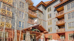 Ein mehrstöckiges Gebäude mit Holzfassade, Steinsäulen und Balkonen.
