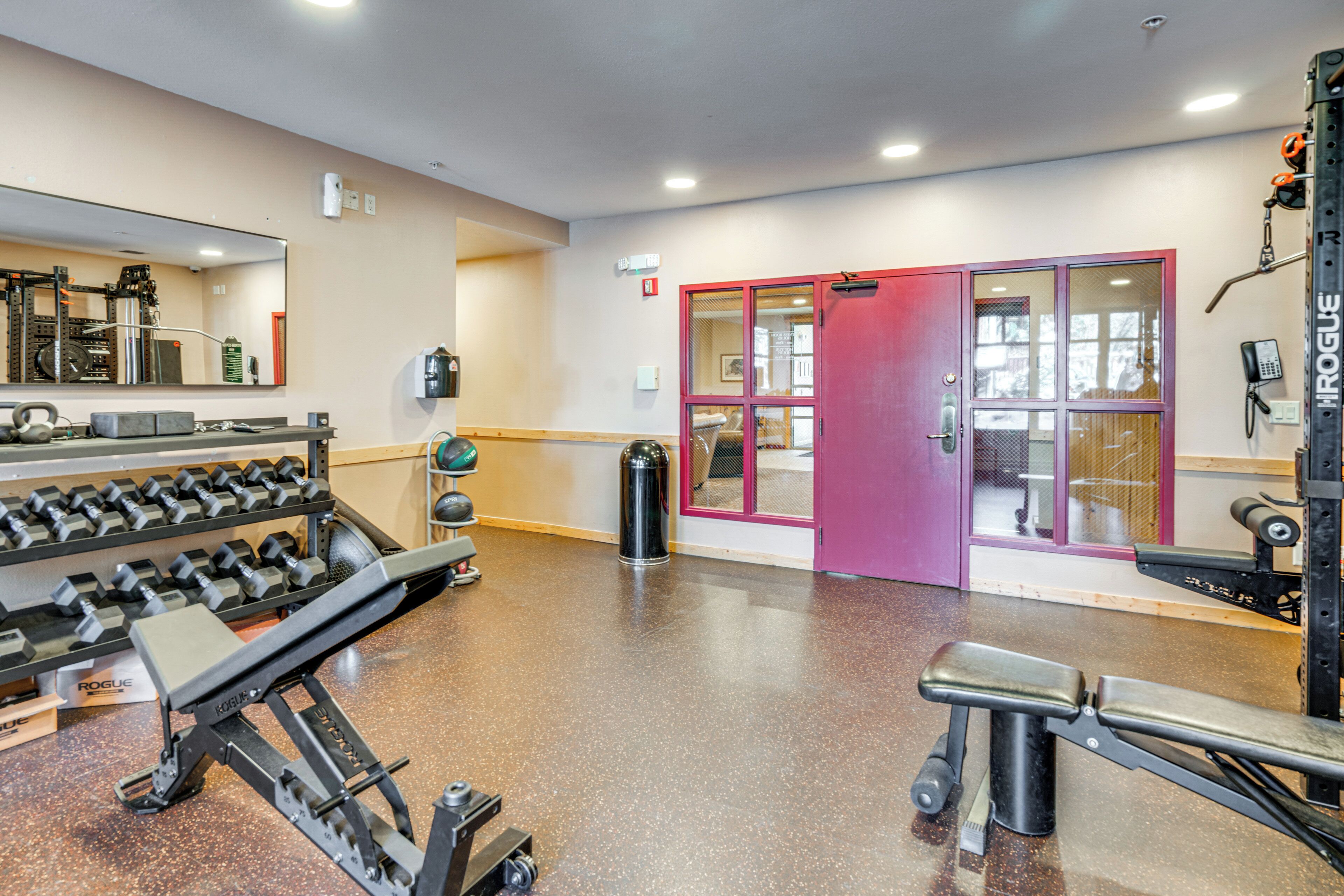 Une salle de sport équipée de matériel de musculation, notamment un banc de développé couché et un mur recouvert de miroirs.