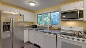 A kitchen with white cabinets, a stainless steel refrigerator, a microwave, a dishwasher, and a stove.