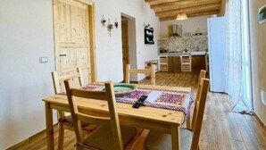 Een eetgedeelte met een houten tafel en stoelen, een hanglamp en een keuken op de achtergrond.