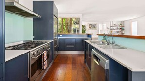 Cocina moderna con estufa a gas, horno y lavavajillas. Se aprecia una ventana con vistas a zonas verdes.