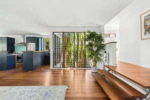 A modern kitchen with dark cabinets, a stainless steel range hood, and a built-in oven. - Elegant 3-Bed Home with Games Room & Balcony (North Balgowlah)
