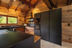A modern kitchen with wooden beams, a large island, and built-in appliances.