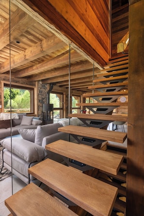 A modern interior with a wooden ceiling, a stone fireplace, and a sofa with cushions. - ✨ Chalet Marcel – Luxury Chalet with Hot Tub, Sauna & Forest Setting (Gérardmer)