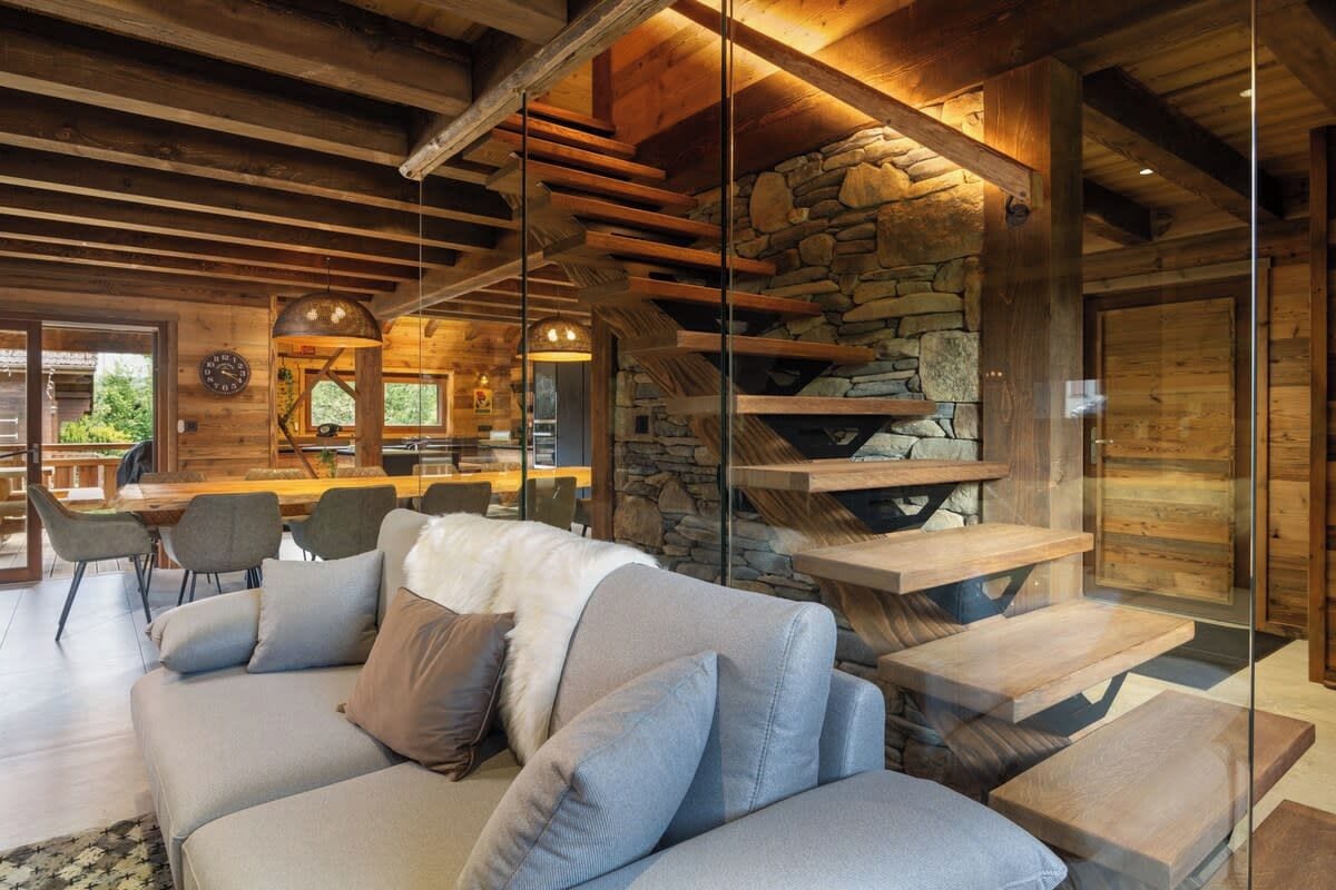 A modern interior with a stone fireplace, a wooden ceiling, and a glass partition.