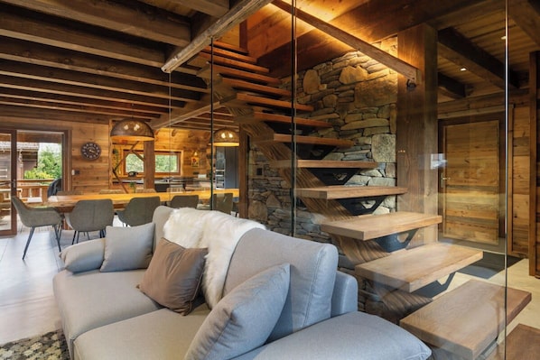 A modern interior with a stone fireplace, a wooden ceiling, and a glass partition. - ✨ Chalet Marcel – Luxury Chalet with Hot Tub, Sauna & Forest Setting (Gérardmer)