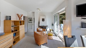 A modern living room with a sofa, a wooden cabinet, a television, and a large window. - Apartment 'Burgblick' with Balcony and Wi-Fi (Sankt Goar)