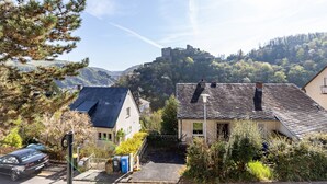 A residential area with houses, a parked car, and a castle on a hill. - Apartment 'Burgblick' with Balcony and Wi-Fi (Sankt Goar)