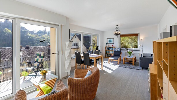 A modern interior with a dining area, seating, and a view through large windows. - Apartment 'Burgblick' with Balcony and Wi-Fi (Sankt Goar)