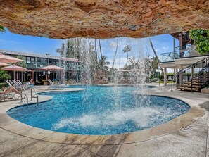 A pool area with a circular pool, lounge chairs, and a waterfall feature. - Luxury 2BD Penthouse with Beach Access and Resort Amenities / PH6 (Miami Beach)