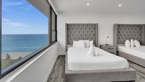 Une chambre d’hôtel avec deux lits, une grande fenêtre donnant sur l’océan et un design moderne.