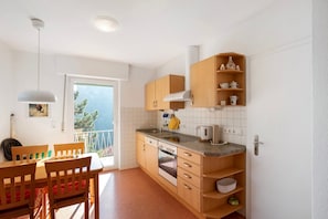 Una cucina moderna con mobili in legno, forno a incasso, lavandino e zona pranzo con tavolo e sedie.