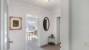 A hallway with a white door, a framed picture, a round mirror, and a small table with a plant. - Holiday Apartment 'Rheinblick' with Balcony and Wi-Fi (Sankt Goar)