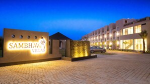 A modern hotel entrance with a sign reading "Sambhav Villas" and a paved driveway leading to the building. - SAMBHAV VILLAS (Pushkar)