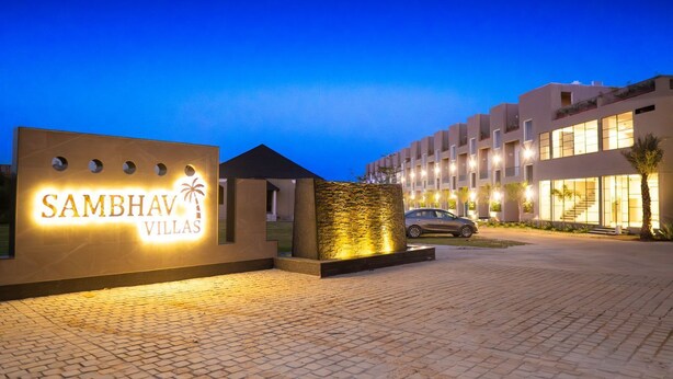 A modern hotel entrance with a sign reading "Sambhav Villas" and a paved driveway leading to the building. - SAMBHAV VILLAS (Pushkar)