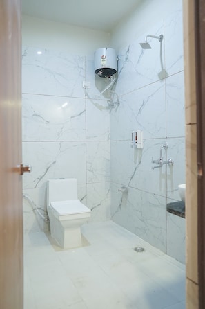 A bathroom with a toilet, a shower, and a hand dryer.