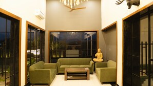 A modern living room with a green sofa set, a wooden coffee table, and a Buddha statue. - SAMBHAV VILLAS (Pushkar)