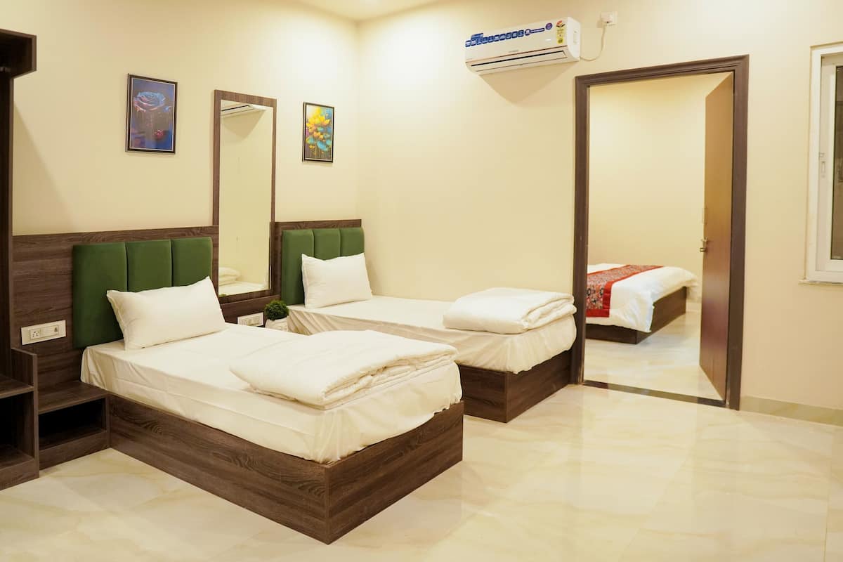 A hotel room with two beds, a mirror, and a door leading to another room.