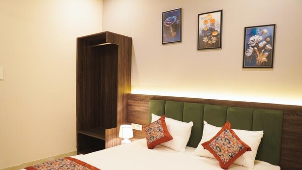 A hotel room with a large bed, green upholstered headboard, and a wooden wardrobe. - SAMBHAV VILLAS (Pushkar)