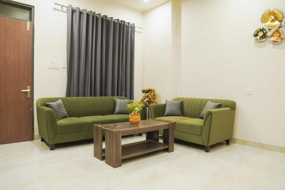 A living room with two green sofas, a wooden coffee table, and a curtain.