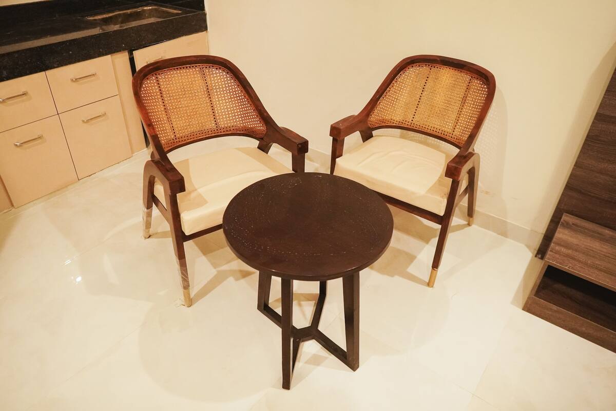 A dining area with two wooden chairs and a round table.