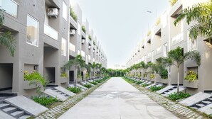 A modern residential building with a central pathway flanked by balconies with plants. - SAMBHAV VILLAS (Pushkar)