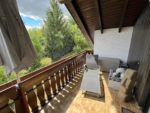 A balcony with a wooden railing, a small table, a chair, and a sofa. - Apartment 'Ausblick' with Balcony and Wi-Fi (Hausen)