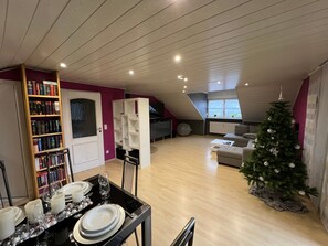 A modern loft-style living space with a dining area, bookshelves, a Christmas tree, and a view through a skylight. - Apartment 'Ausblick' with Balcony and Wi-Fi (Hausen)