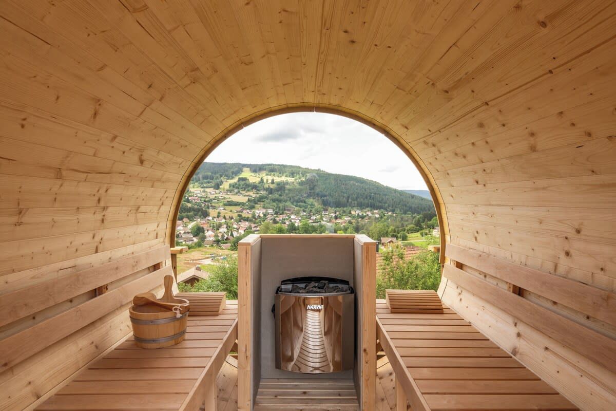A sauna with a view of a village through an arched wooden ceiling.