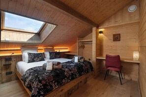 A bedroom with a bed, a desk, a chair, and a skylight.