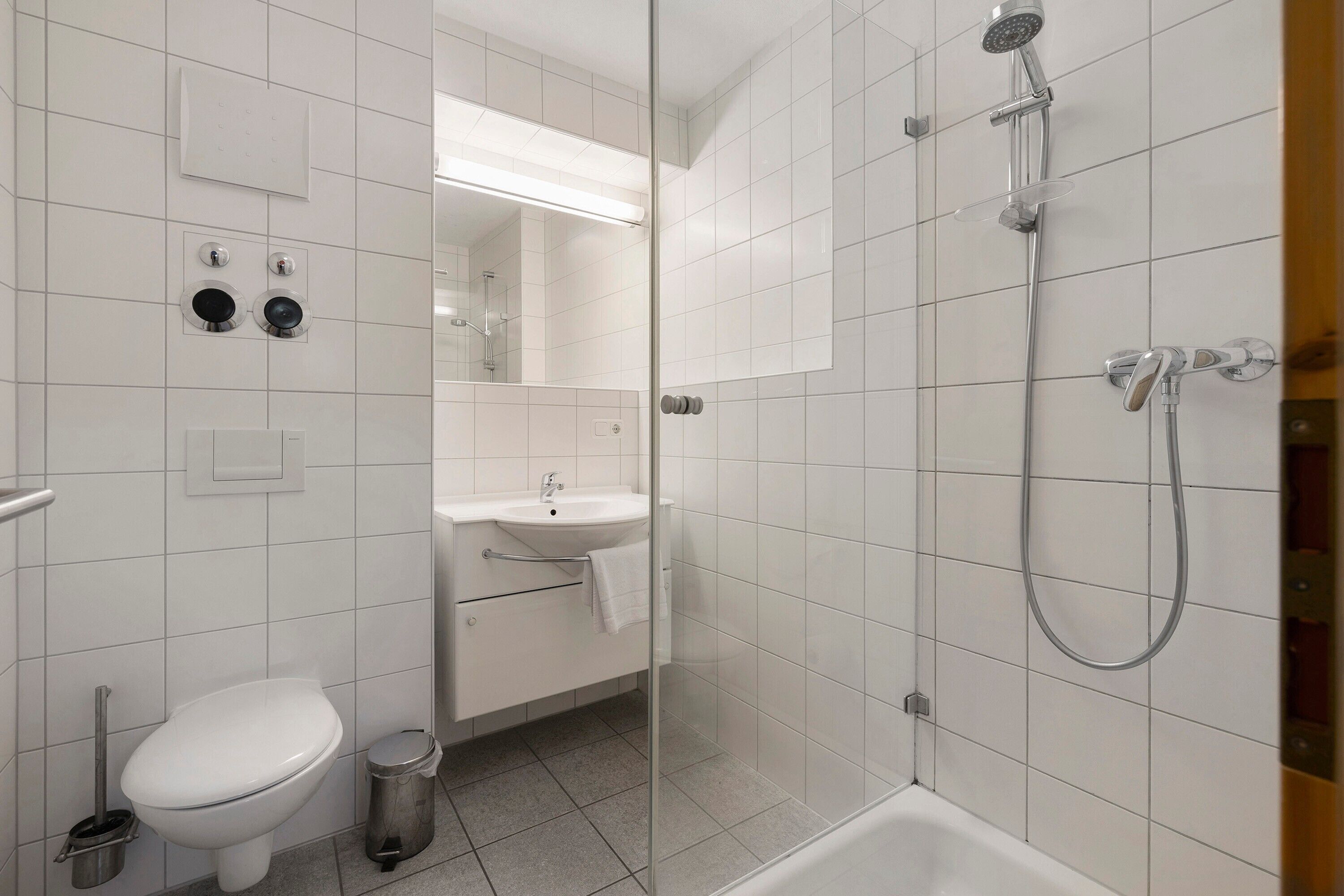 Un baño moderno con inodoro, lavamanos y ducha.