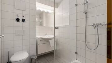 Un baño moderno con inodoro, lavamanos y ducha.