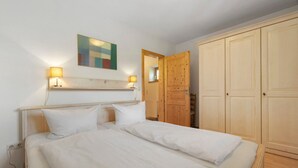 Une chambre à coucher avec un lit, des lampes de chevet, une armoire en bois et un tableau au mur.