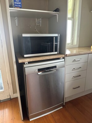 Compact kitchen with microwave oven and stainless steel dishwasher.