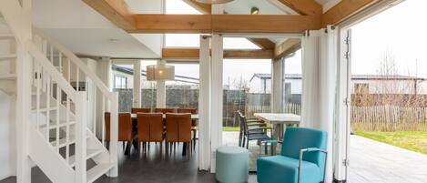 A modern interior with a staircase, dining area, and large windows.